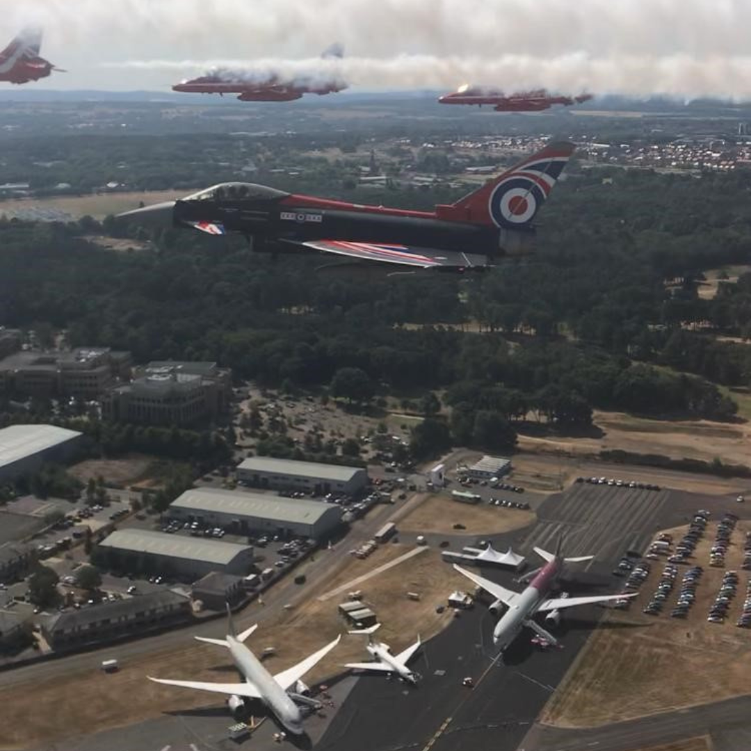 Image shows Red Arrows and Typhoons in flight over an airport.
